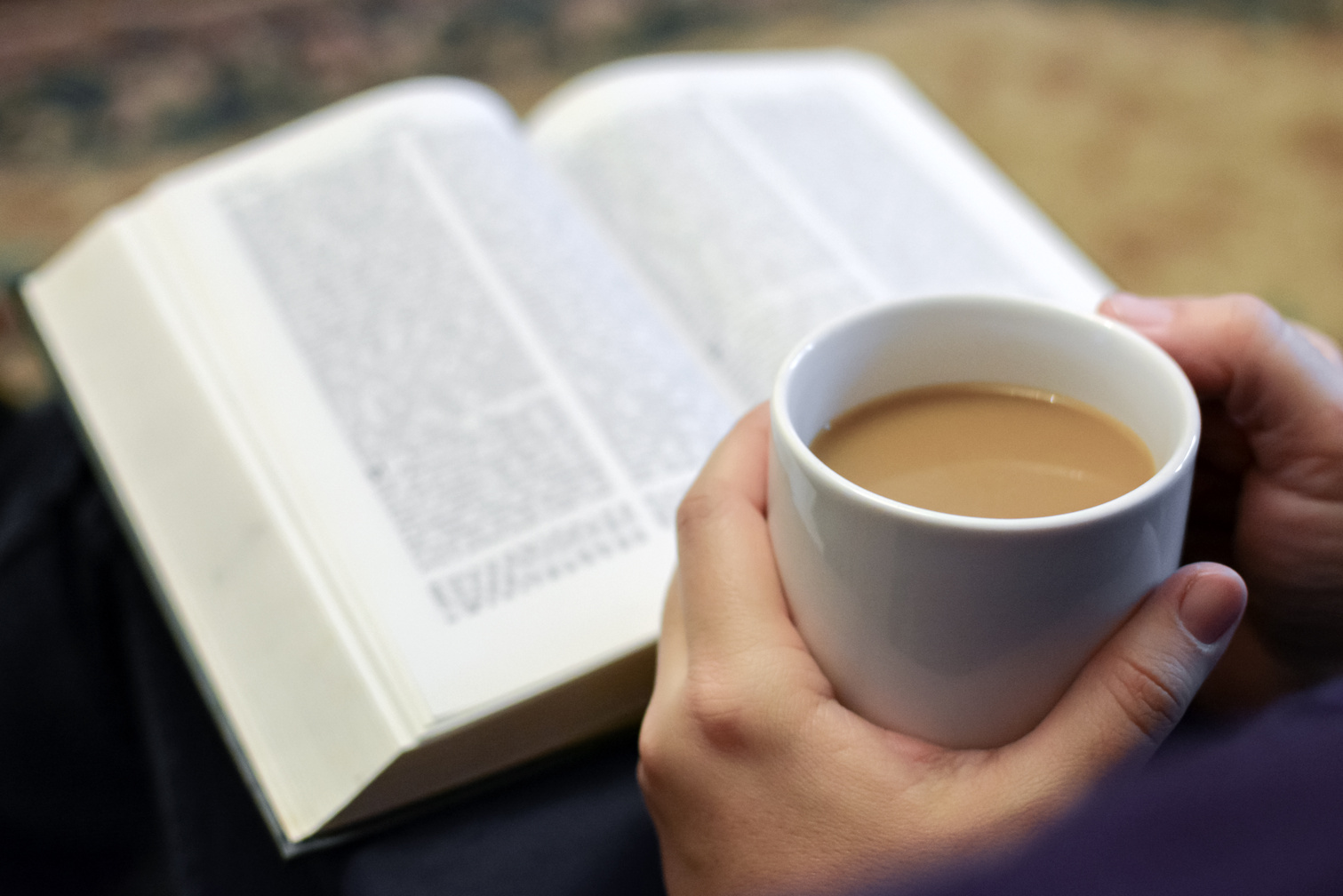 Cup of coffee in hands, reading bible